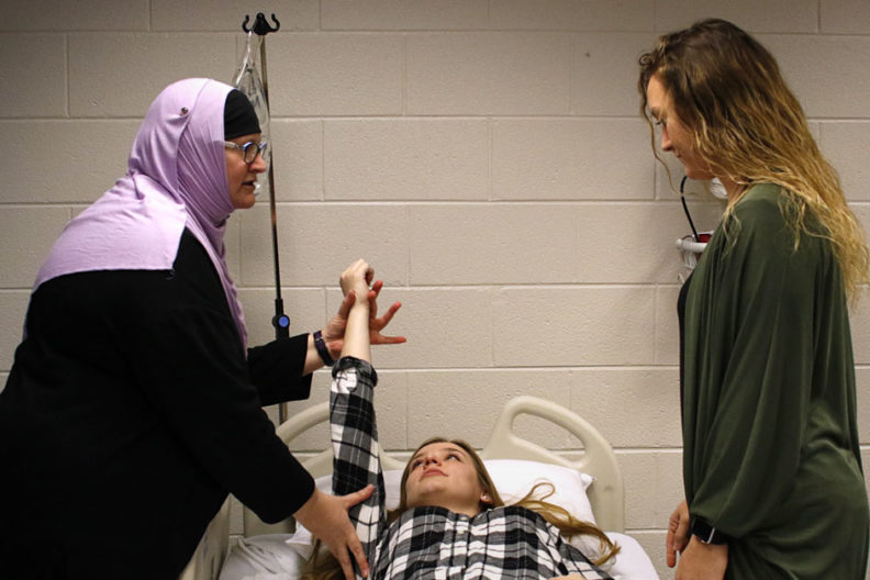 An occupational therapy instructor demonstrates on a patient in a classroom setting at Elmhurst University.