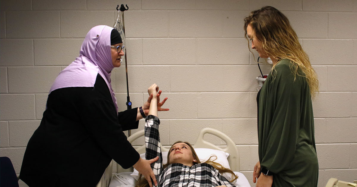 An occupational therapy instructor demonstrates on a patient in a classroom setting at Elmhurst University.
