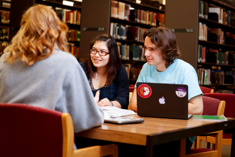 Elmhurst College students discuss their studies at a table in the A.C. Buehler Library on campus.