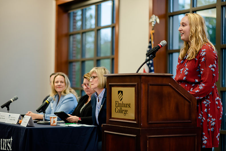 A student speaks at the podium while panelists look on during the Elmhurst College Master's Entry in Nursing Practice Legislative Breakfast in October of 2019.
