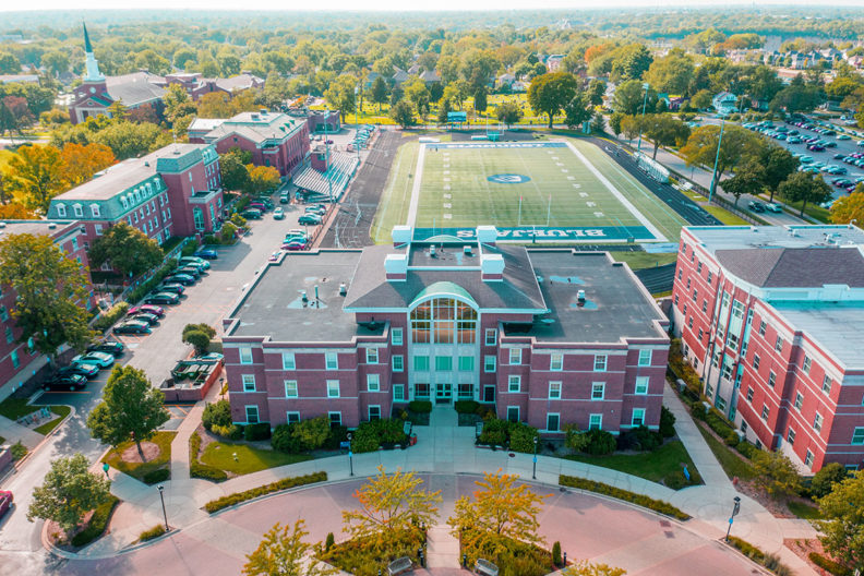 Circle Hall is in the foreground of an aerial photograph of the Elmhurst College campus, with Langhorst Field in the background.