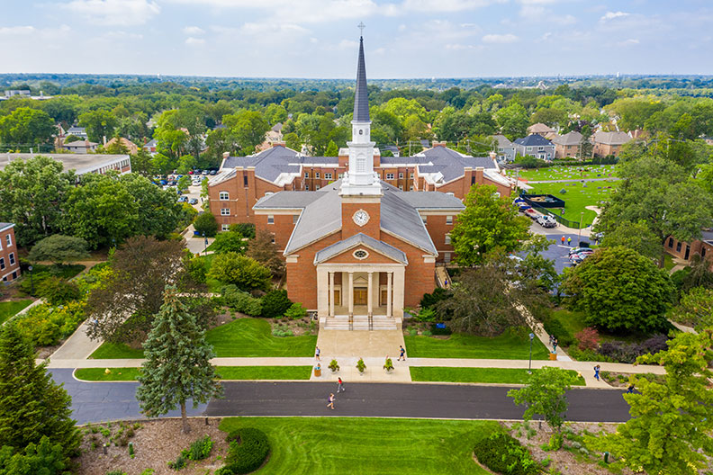 An aerial photograph of the Elmhurst University campus shows Hammerschmidt Memorial Chapel.