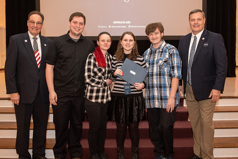 The winner of the 2020 American Dream Fellowship Competition at Elmhurst College holds her award and poses for a photo with friend, family and Elmhurst administrators.