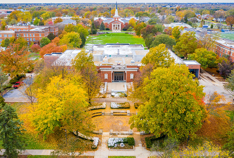 An aerial photograph of the Elmhurst College campus shows Kranz Forum and the Frick Center in the foreground, with Hammerschmidt Memorial Chapel in the background.