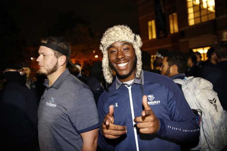 A Black Elmhurst University student smiles and points at the camera during a Homecoming pep rally.