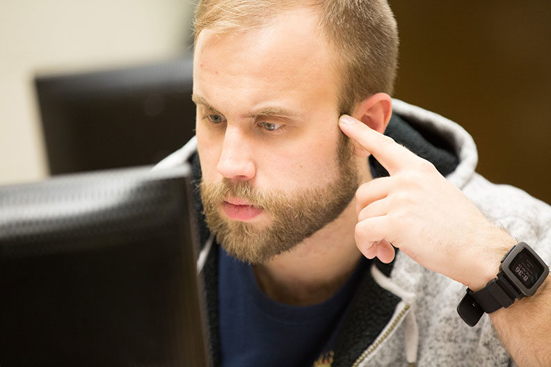 An Elmhurst University graduate student looks intently at a computer monitor.