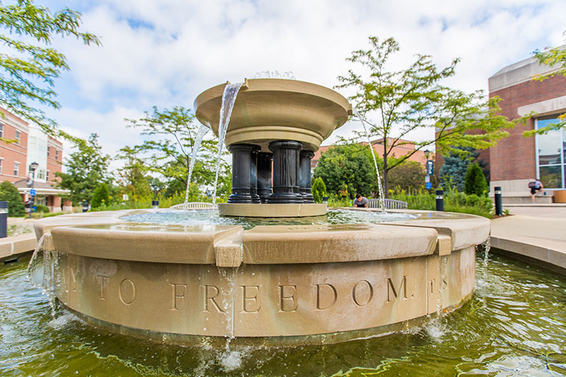 A photo of Alumni Fountain on the campus of Elmhurst University in the Chicago suburbs. The engraved words "To Freedom" are visible.