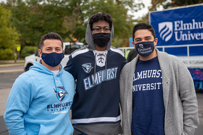 Three students wearing Elmhurst University spirit wear at the Homecoming Parade.