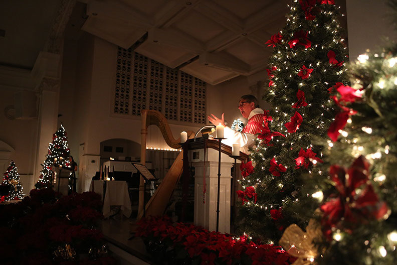 Elmhurst University Chaplain H. Scott Matheney speaks at a lecturn in the darkened Hammerschmidt Memorial Chapel during the annual Festival of Lessons and Carols.