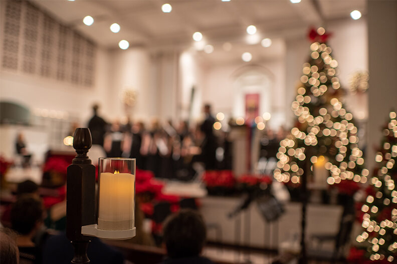 A candle and a Christmas tree decorate Hammerschmidt Memorial Chapel for the annual Festival of Lessons and Carols performance at Elmhurst University.