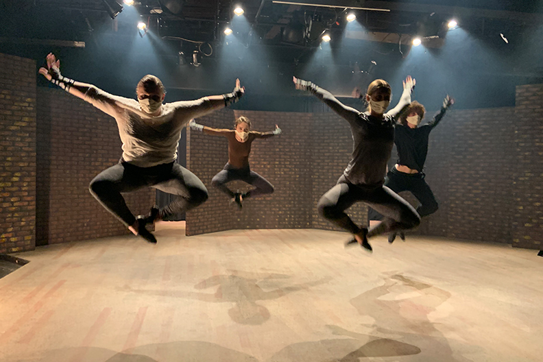 Four dance students jumping in the air while performing their dance routine in the Elmhurst University Mill Theatre.