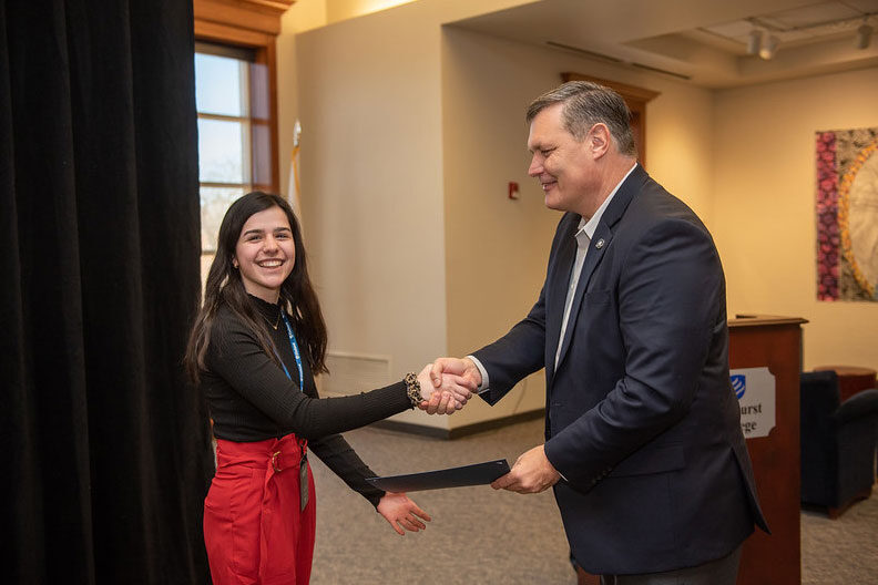 A female student shakes hands with Elmhurst University President Troy VanAken as she is honored during the 2020 Niebuhr Service to Society Competition.