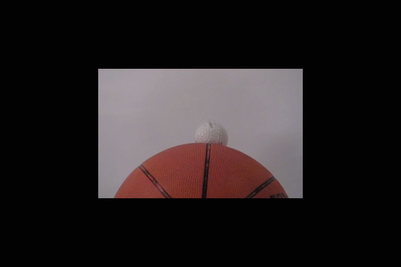 Image of a golf ball colliding with a basketball.