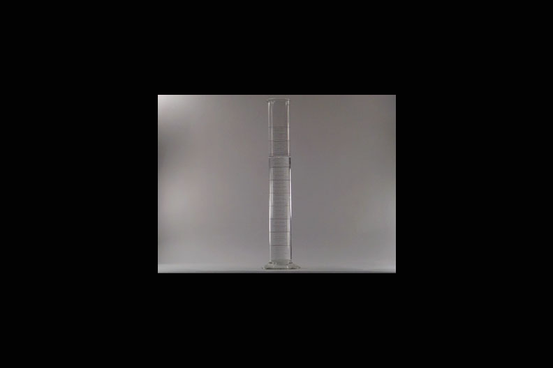 A photo of a hollow clear tube with a ball being dropped down it.
