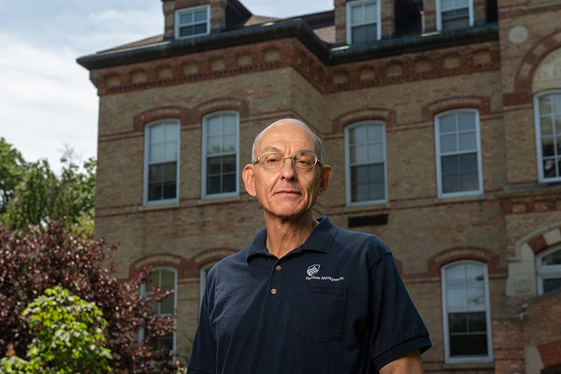 Mark Wakely, Services Manager at Elmhurst University, in front of the Old Main building on campus.