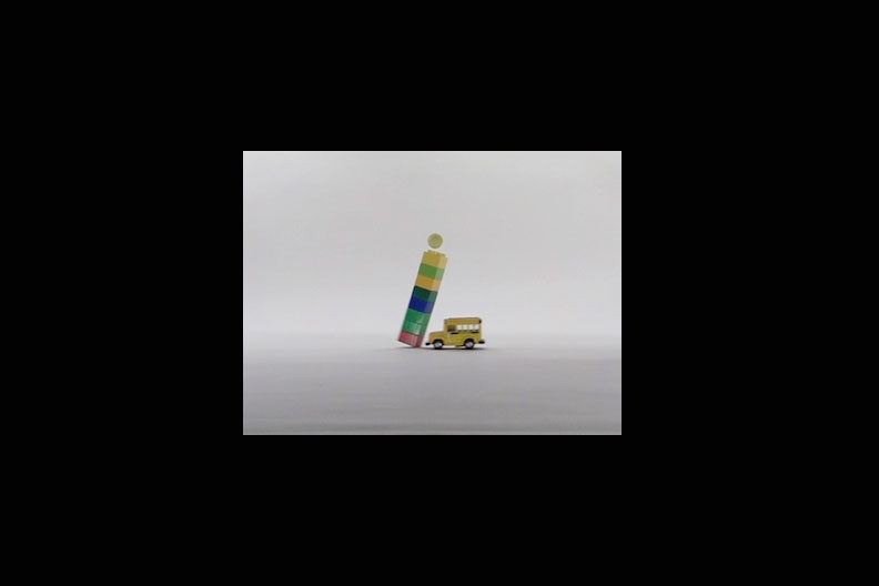 A photo of a toy car colliding with a tower of Lego bricks with a ball resting atop the tower.