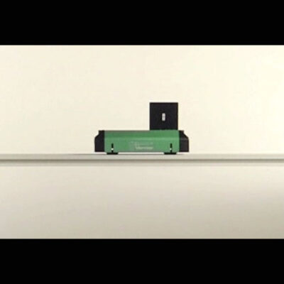 A photo of a green dynamics cart rolling horizontally on a silver track.