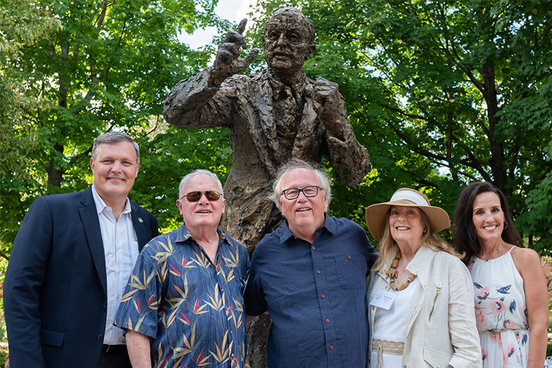 Elmhurst University President Troy D. Van Aken and longtime Jazz Band director Doug Beach with donor Maureen Heaken in front of the Niebuhr statue on campus.