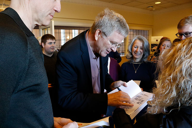 PBS travel TV host Rick Steves signs a book during a speaking engagement at Elmhurst University in 2018.