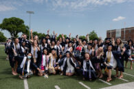 A large group of Elmhurst University graduates pose for a photo on the Langhorst football field for the 2021 Commencement ceremony.