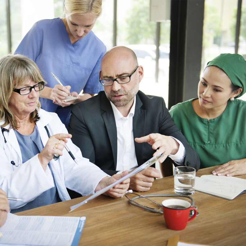 A group of DNP nurses discuss medical findings at a conference room table.