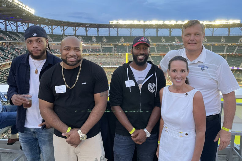 A group of Elmhurst University alumni pose for a group photo at a baseball game in Atlanta as part of the 2021 President's Road Trip.