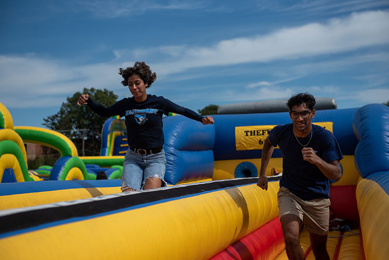 A female and male student run on an inflatable obstacle course during homecoming at Elmhurst University.