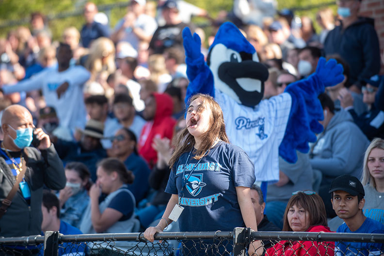 A female student cheers on the Elmhurst University football team at the 2021 Homecoming game.