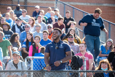 A male student cheers on the Elmhurst University football team during the 2021 Homecoming game.
