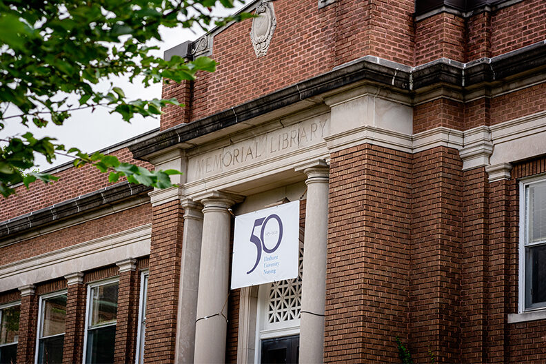 Exterior of Memorial Hall with a 50 years of Elmhurst University Nursing banner.