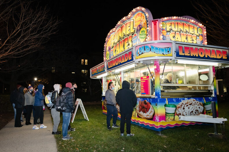 A funnel cake and soda stand is lit up at night during Elmhurst's Founders Day celebration.