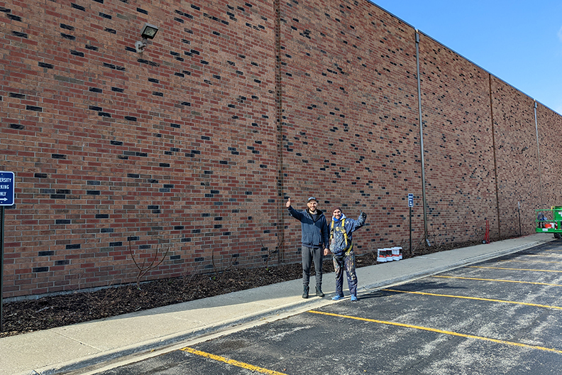 Rafael Blanco and Andrew Sobol stand in front of the north-facing wall of R.A. Faganel Hall before they begin painting the mural.