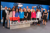 The group of speakers at the TedxElmhurstUniversity pose for a group picture in front of the event signage.