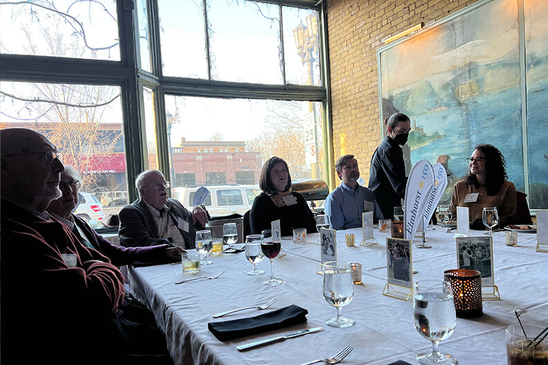 A group of Elmhurst University alumni sit at a dinner table during the 2022 President's Road Trip event in Minneapolis, MN.