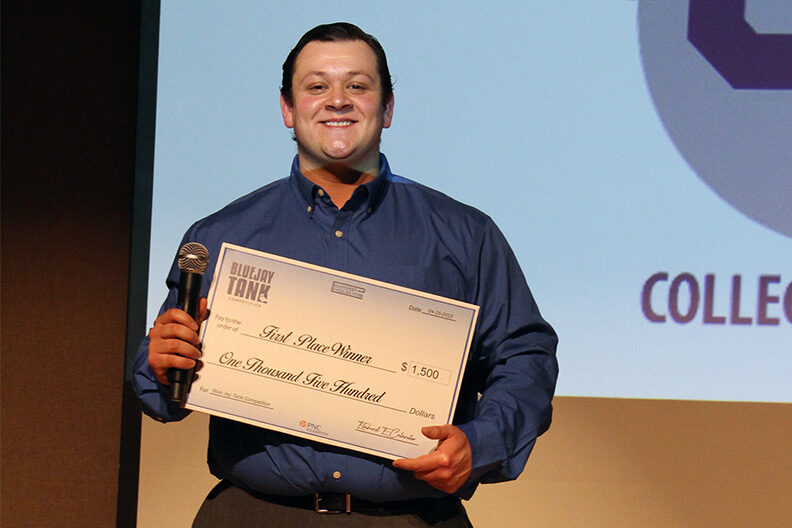 Elmhurst University student Mark Picardi holds his prize money check for winning the Bluejay Tank business pitch competition.