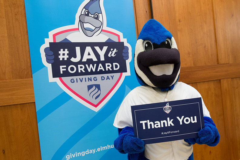 Elmhurst University mascot Victor E. Bluejay holds a sign that reads "Thank You" on the University's annual Giving Day event.