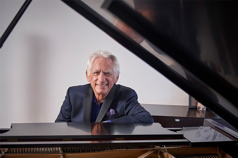 Jazz pianist David Benoit sitting at a piano.