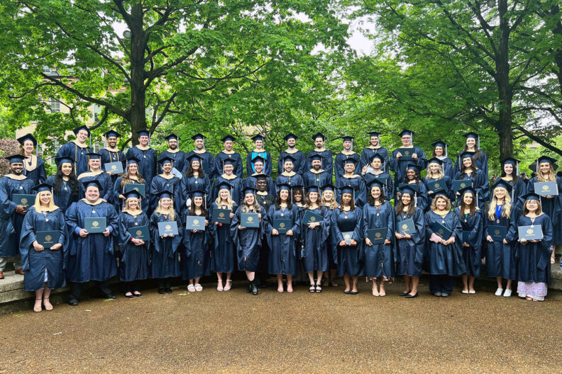 Group photo of the 2022 cohort of Elmhurst University MBA graduates in their caps and gowns at Commencement.