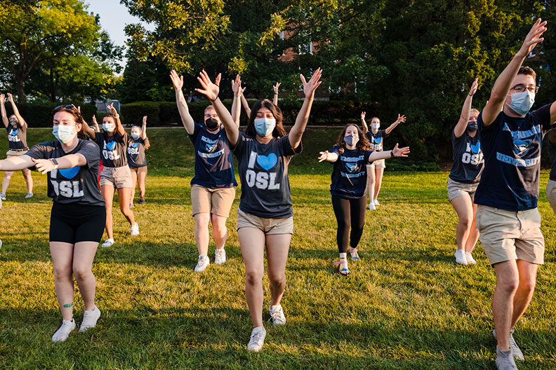 A group of Elmhurst University students raise their arms during a dance routine at the 2021 New Student Orientation event.