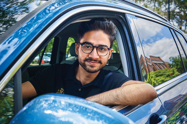 Elmhurst University student Aman Dhiman is shown behind the wheel of a blue car.