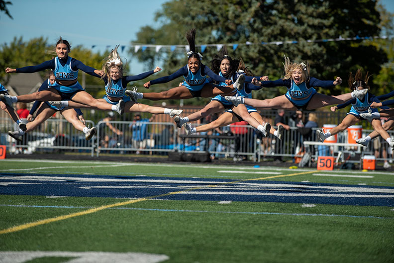 Elmhurst University cheerleaders leap in the air during a routine at the Homecoming football game on Oct. 1, 2022.
