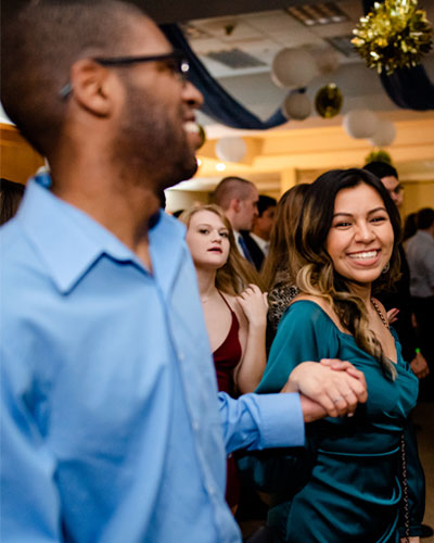 Two students smile and hold hands while dancing at the Elmhurst University Presidents' Ball event.