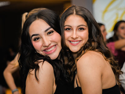 Two female students putting their heads together and smiling for a picture during the Elmhurst University Presidents' Ball event.