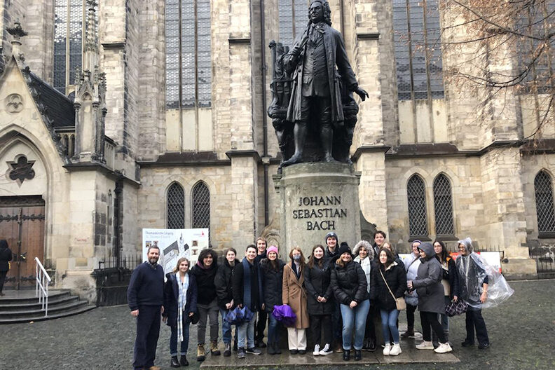 A group of students stand in front of a statue of Mozart