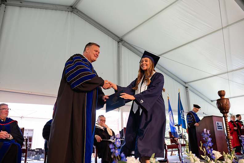 Student receiving their diploma from president Troy VanAken