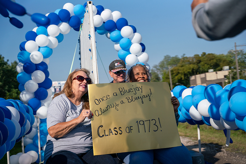 Three people smiling with a sign saying "Once a Bluejay, Always a Bluejay - Class of 1973"