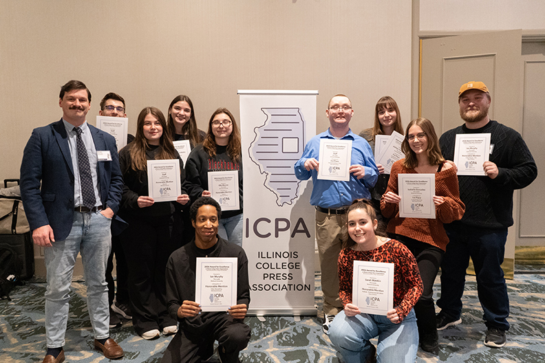 A group of people holding certificates in front of a banner reading IPCA