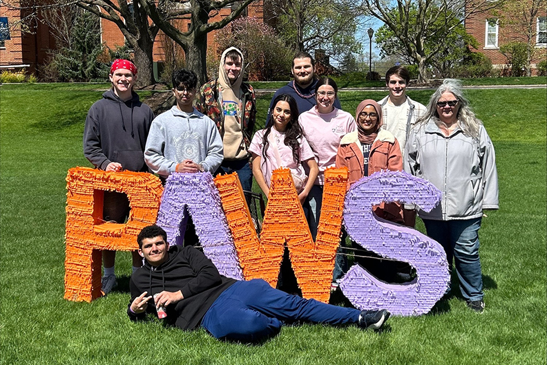 Students standing behind PAWS sign.